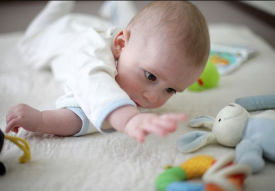 my baby try to grasp his toy to put in his mouth